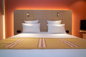 1 cama grande con almohadas blancas en una habitación en Nash Airport Hotel, en Ginebra