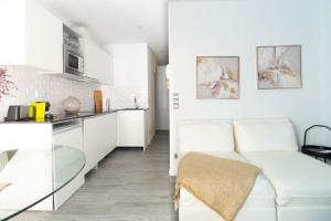 sala de estar blanca con sofá y cocina en Terra Boutique Apartment, en Girona