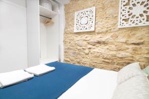 1 dormitorio con cama y pared de piedra en Terra Boutique Apartment, en Girona
