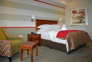 a hotel room with a bed and a chair at Indaba Lodge Gaborone in Gaborone