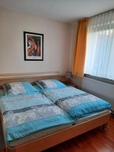 a bedroom with a bed with blue sheets and a window at Ferienwohnung Cubanzeneck in Kühlungsborn