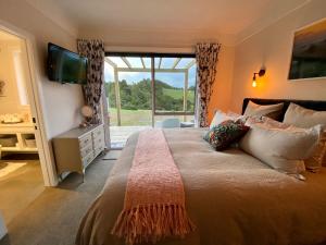 a bedroom with a large bed with a large window at Kauri Glen BnB in Te Arai