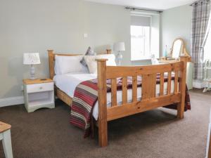 a bedroom with a wooden bed and a desk at Todlaw Farm House in Jedburgh