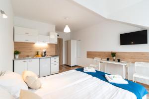 a room with a large white bed and a kitchen at Willa Wena in Ustka