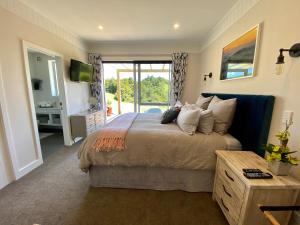 a bedroom with a large bed and a sliding glass door at Kauri Glen BnB in Te Arai