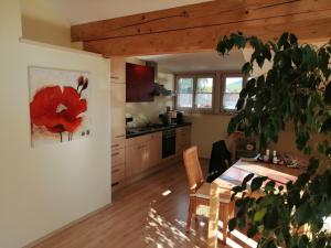 una cocina con una mesa y un cuadro de flores rojas en la pared en Ferienhaus Scholz, en Rieden