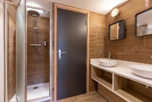 a bathroom with a shower and two sinks at Hotel Base Camp Lodge - Bourg Saint Maurice in Bourg-Saint-Maurice