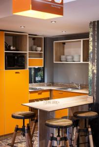 a kitchen with yellow cabinets and bar stools at Hotel Base Camp Lodge - Bourg Saint Maurice in Bourg-Saint-Maurice