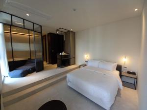 a bedroom with a large white bed and a mirror at Hotel Libre in Siheung