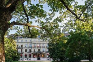 ein großes weißes Gebäude mit Bäumen davor in der Unterkunft Hôtel Métropole Genève in Genf