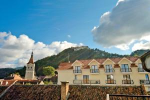 a building and a church with a mountain in the background at ApartamentS in Râşnov