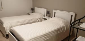 two beds with white sheets in a room at Civico 54 - Locanda & Bistrò in Nonantola