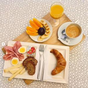 a table with a plate of breakfast food and a cup of coffee at Hotel Les Arcades in Geneva
