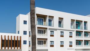 an apartment building with a palm tree at Kefalos Damon Hotel Apartments in Paphos