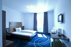 una camera d'albergo con letto e TV di Hotel City Oase Lb a Ludwigsburg