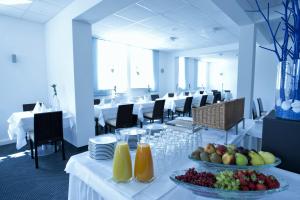 - une salle à manger avec des tables blanches et des fruits dans l'établissement Hotel City Oase Lb, à Ludwigsbourg
