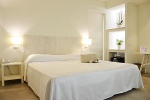 a bedroom with a white bed with a laptop on it at Hotel Costa dei Fiori in Santa Margherita di Pula