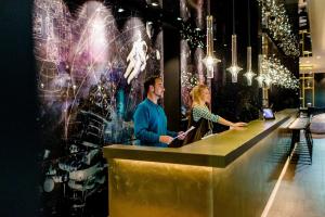 a man and woman standing at a bar in a restaurant at Motel One Nürnberg-Plärrer in Nuremberg