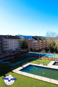 a swimming pool with a tennis court and some buildings at Altur 5 Jaca in Jaca