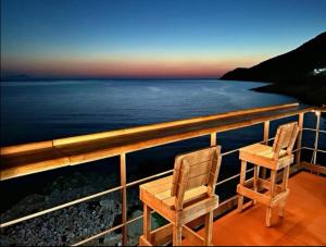 2 sedie sedute su un balcone affacciato sull'oceano di Kampos Home ad Apollonía