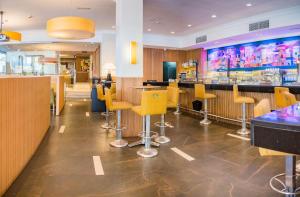 un restaurante con sillas amarillas y un bar en Hotel Opera, en Madrid