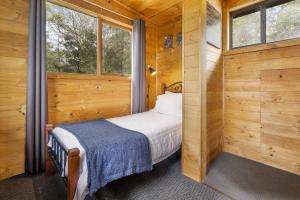 a small bedroom with a bed in a wooden cabin at Mole Creek Cabins in Mole Creek