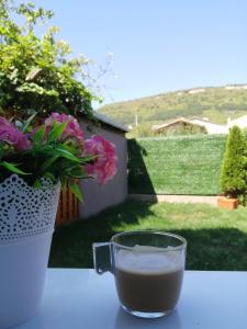 a cup of coffee sitting on a table next to a vase of flowers at La Piazza Hotel in Shumen