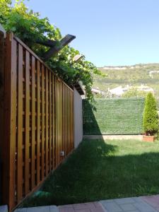 a wooden fence with green grass next to a yard at La Piazza Hotel in Shumen