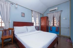 een slaapkamer met een bed, een stoel en ramen bij OYO 89873 Nurbayu Chalet in Kuantan