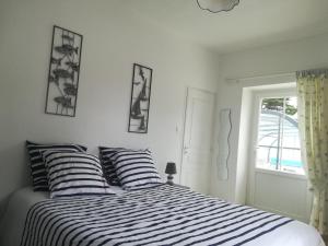 a bedroom with a bed with striped pillows and a window at Gite LES BALISES- BABORD-Maisons de bord de mer avec spa -SAINT GILLES CROIX DE VIE - 27 Avenue NOTRE DAME in Saint-Gilles-Croix-de-Vie