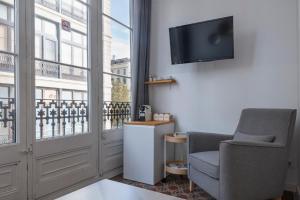 sala de estar con silla, TV y ventana en Hostalin Barcelona Gran Via, en Barcelona