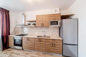 a kitchen with wooden cabinets and a stainless steel refrigerator at KZN Apartments - Art City 2 in Kazan