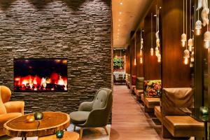 a lobby with a fireplace and tables and chairs at Motel One Salzburg-Süd in Salzburg