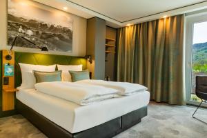 a bedroom with a large white bed and a window at Motel One Salzburg-Süd in Salzburg