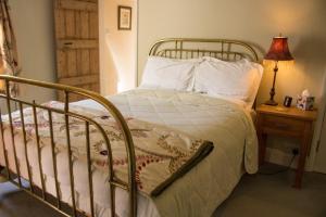 a bed with a metal frame and white sheets and pillows at The Old Post House in Naseby