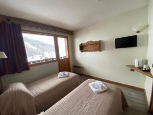 a hotel room with two beds and a window at Les Rhododendrons in Plagne 1800