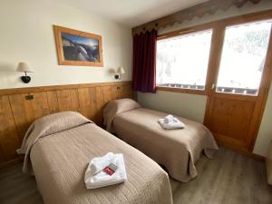 two beds in a hotel room with towels on them at Les Rhododendrons in Plagne 1800