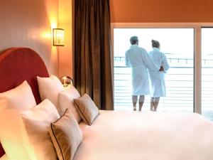 a hotel room with two beds and a mirror at Hotel Mercure Roscoff Bord De Mer in Roscoff