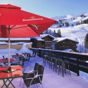 a group of tables and chairs in the snow with an umbrella at Les Rhododendrons in Plagne 1800