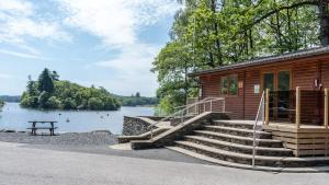 a wooden cabin with stairs next to a lake at Hill Of Oaks in Windermere