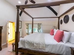 ein Schlafzimmer mit einem Himmelbett und roten Kissen in der Unterkunft Historical Cottage Escape BIG in Burnham