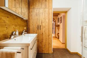 ein Badezimmer mit einem weißen Waschbecken und einer Holzwand in der Unterkunft PRIVATE SUITES in Traunkirchen