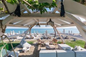 a beach with umbrellas and chairs and the ocean at Blue Carpet Luxury Suites in Pefkochori