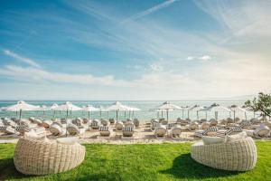a group of chairs and umbrellas on the beach at Blue Carpet Luxury Suites in Pefkochori