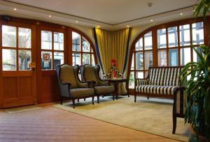 ein Wartezimmer mit Stühlen, einem Tisch und Fenstern in der Unterkunft Hotel Vier Spitzen in Lauenförde