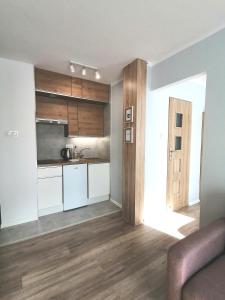 a kitchen with white cabinets and a wooden floor at City Apartments Studio in Zgorzelec
