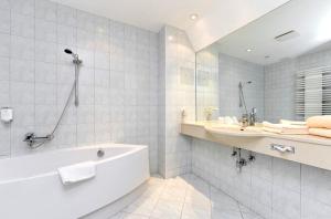 un bagno bianco con vasca e lavandino di Parkhotel a Dallgow