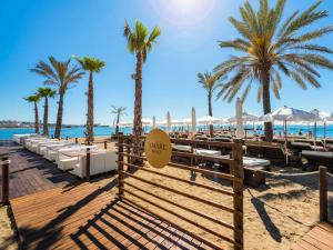 a beach with chairs and palm trees and the ocean at Amàre Beach Hotel Marbella - Adults Only Recommended in Marbella