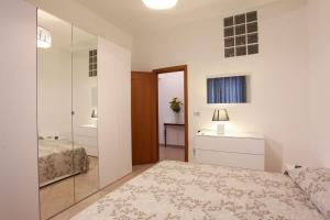 Habitación blanca con cama y espejo en Afrodite appartamento Ballarò, en Palermo