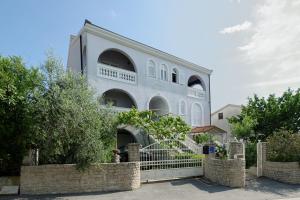 a white building with a fence in front of it at Apartments Udovicic HH in Medulin